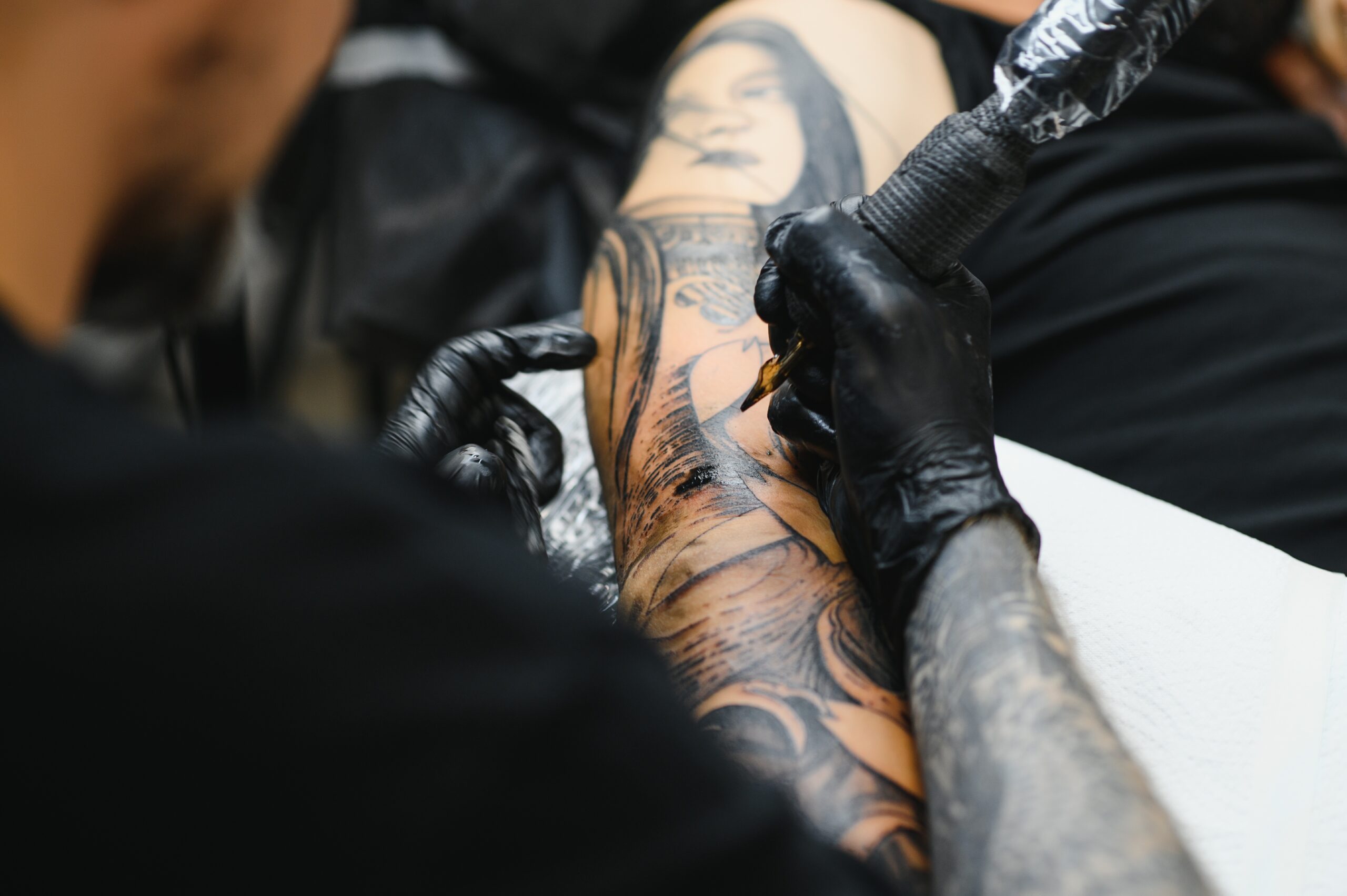 tattooist with his machine tattooing on the arm with the design drawn, concept of art and design